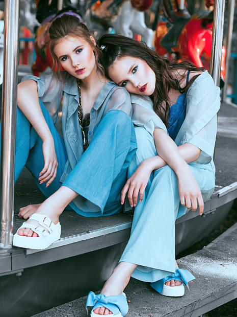 На фотографии девушки фото модели онисидят на ступеньках прижавшись друг к другу.