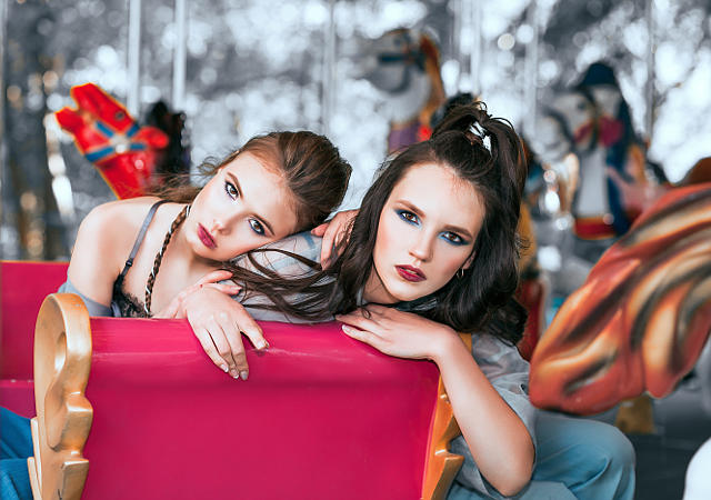 На фотографии две девушки модели, они катаяться на карусели.