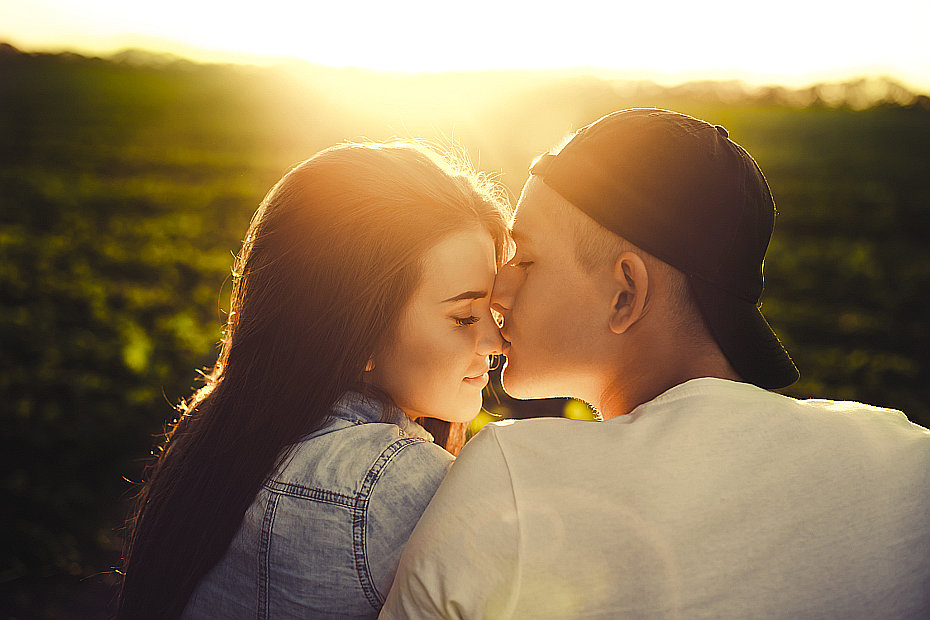 Фотография молодой пары на фоне расвета, парень целует девушку в нос, девушка с черными красивыми волосами в джинсовой курточке