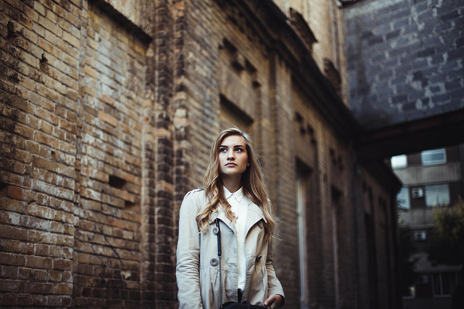 Фотография девушки блондинки с длиными красивыми волосами с большими карими глазами на фоне стариного здания из кирпича