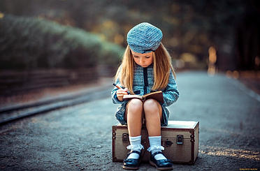 На фото маленькая девочка которая сидит на чемодане фотограф запечатлел удивительный момент.