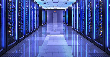 На фотографии красивый дата центр. В светло-синем цвете. Со светящимися серверными шкафами.